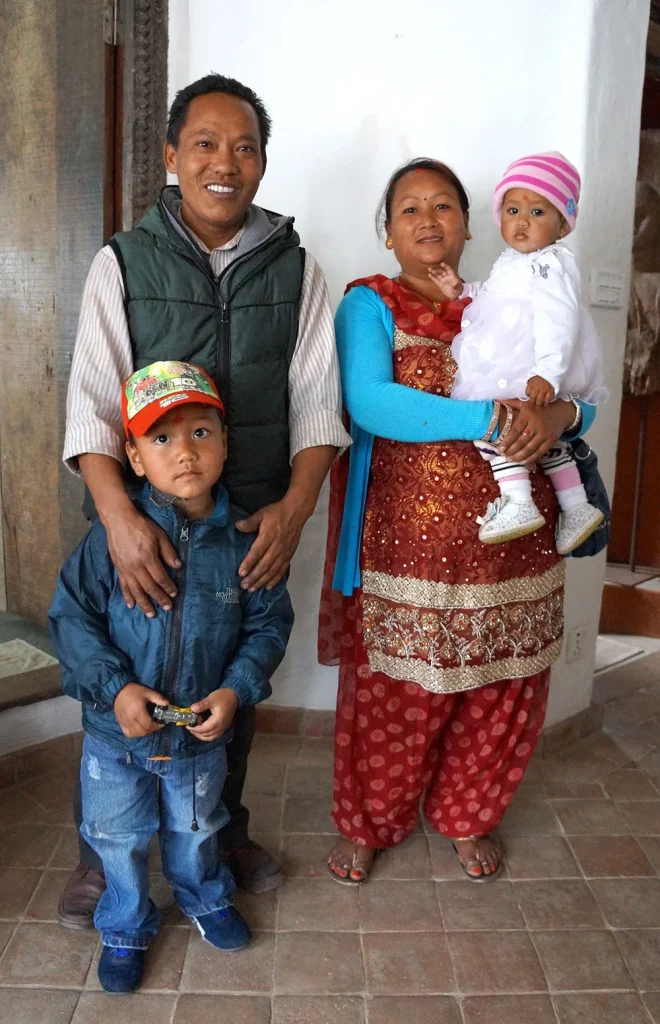 A father and mother stand with their young son and baby daughter inside their home in Nepal